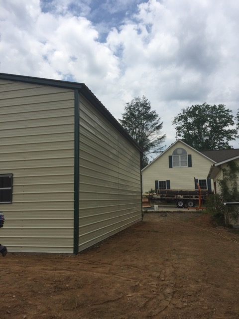 2 Side view of a commercial metal garage building, with beige sides and green trim.