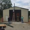Crew building a commercial metal garage, attaching the trim.
