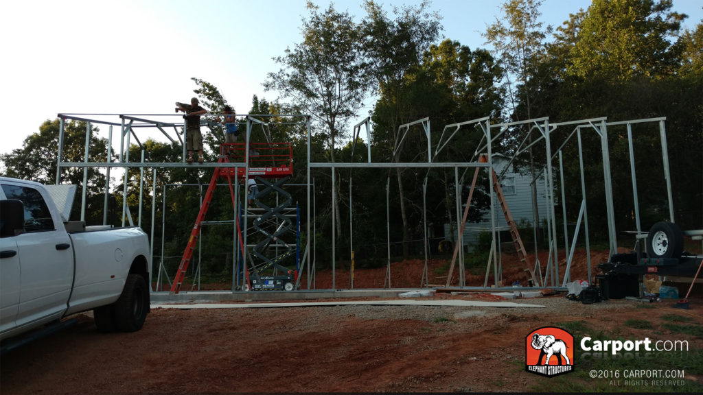 Workers stand on the bracing of the roll-up garage door.
