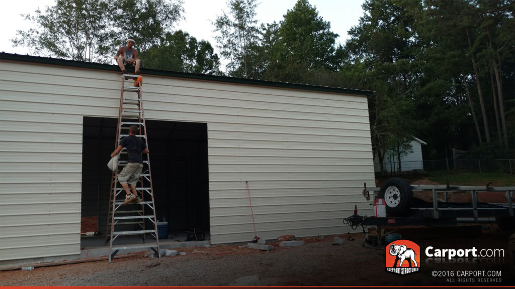 Two crewmen scale a ladder in order to adjust the roof panels.