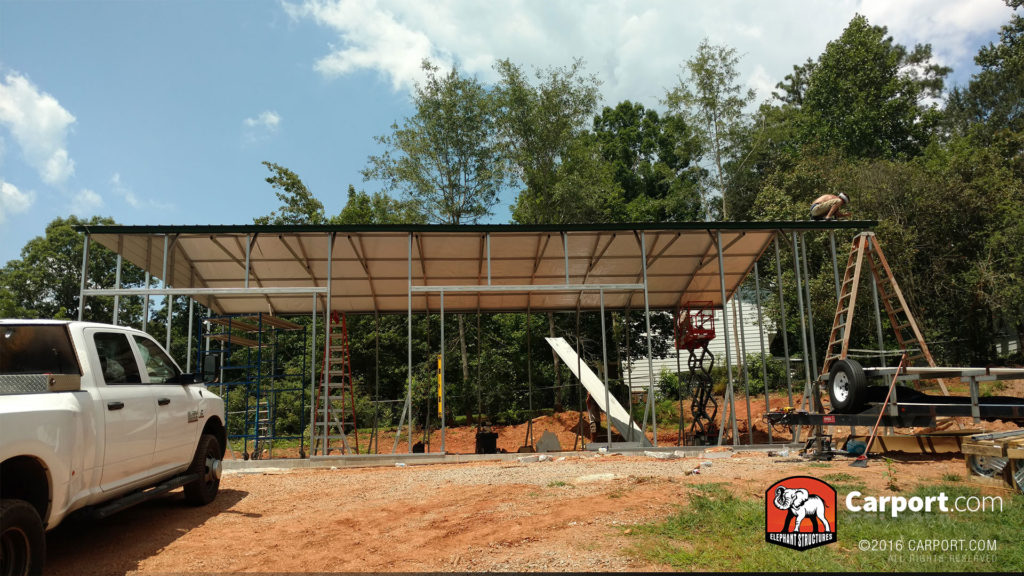 Entire view of the framing of the building and a worker on the roof.