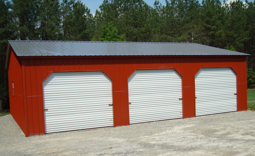 Three car steel garage with 45 degree angle trim, red walls, and galvalume roof.